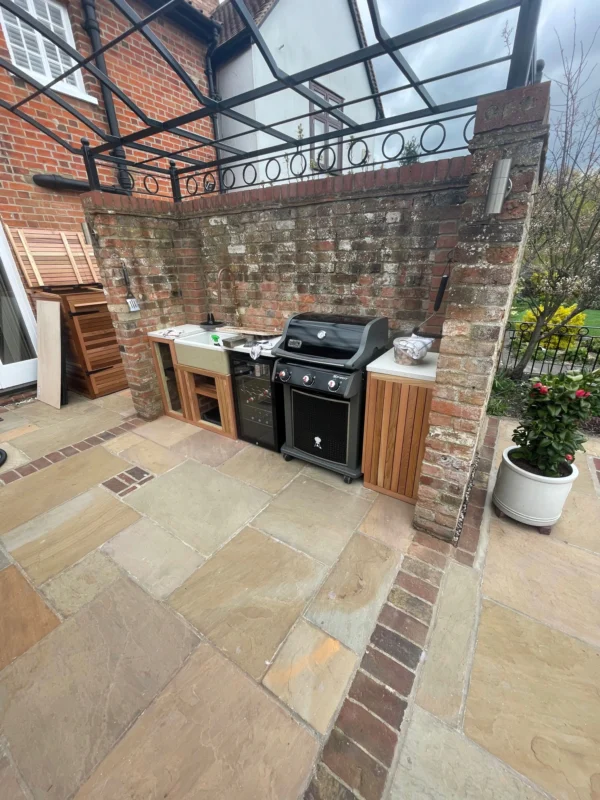 An outdoor kitchen with a wine cooler and black cooker.