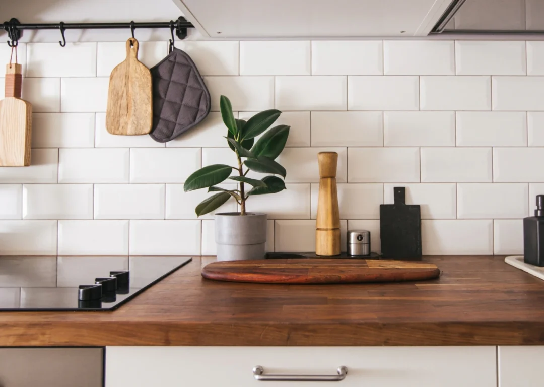 A dark wooden kitchen bench with a potted plant and cooking utensils on it.