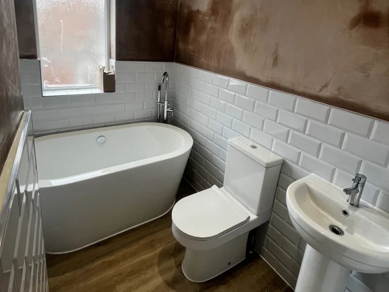 A small bathroom with white tiles and brown walls.