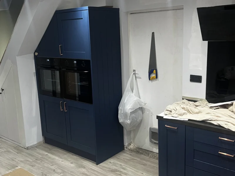 Navy blue kitchen cabinetry being installed.