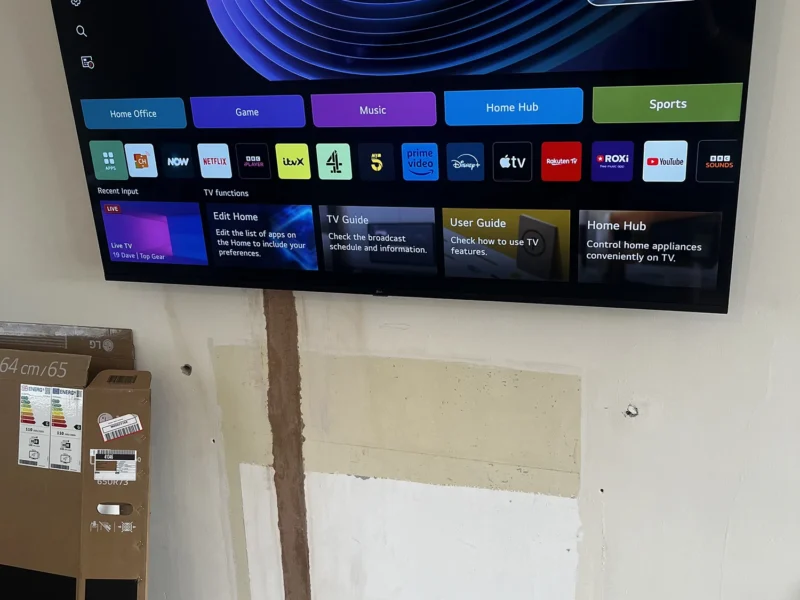 A wall-mounted TV above a box placed on the floor, creating a modern living room setup.