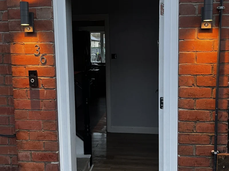A door on a brick building illuminated by a light, showcasing its entrance and architectural details.