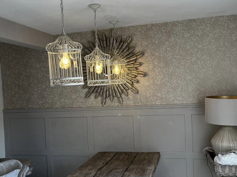 A dining room featuring a wooden table surrounded by four chairs, with soft lighting creating a warm atmosphere.