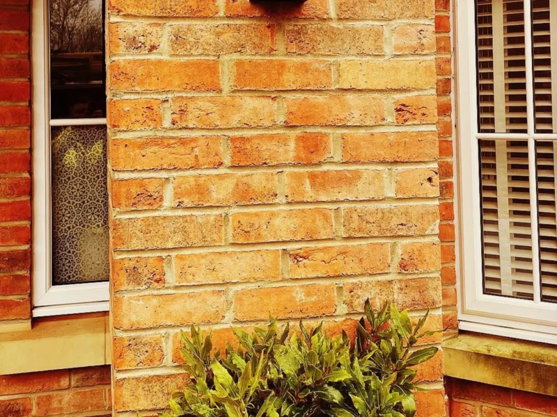 A brick wall featuring an outdoor light mounted on it.