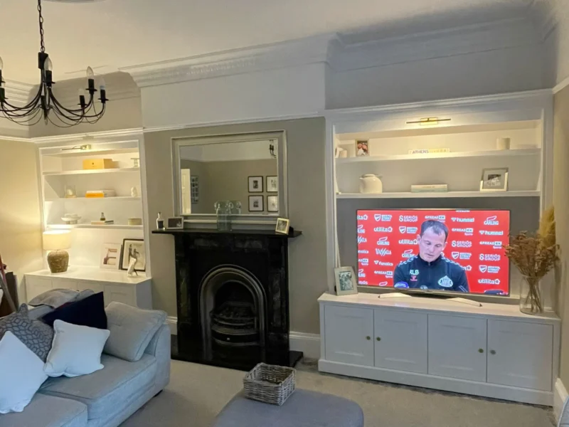 A cosy living room featuring a wall-mounted television and comfortable seating arrangements.